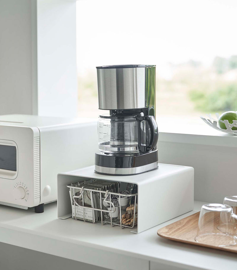 White Yamazaki Home Stackable Countertop Shelf with a coffee pot above and a basket underneath