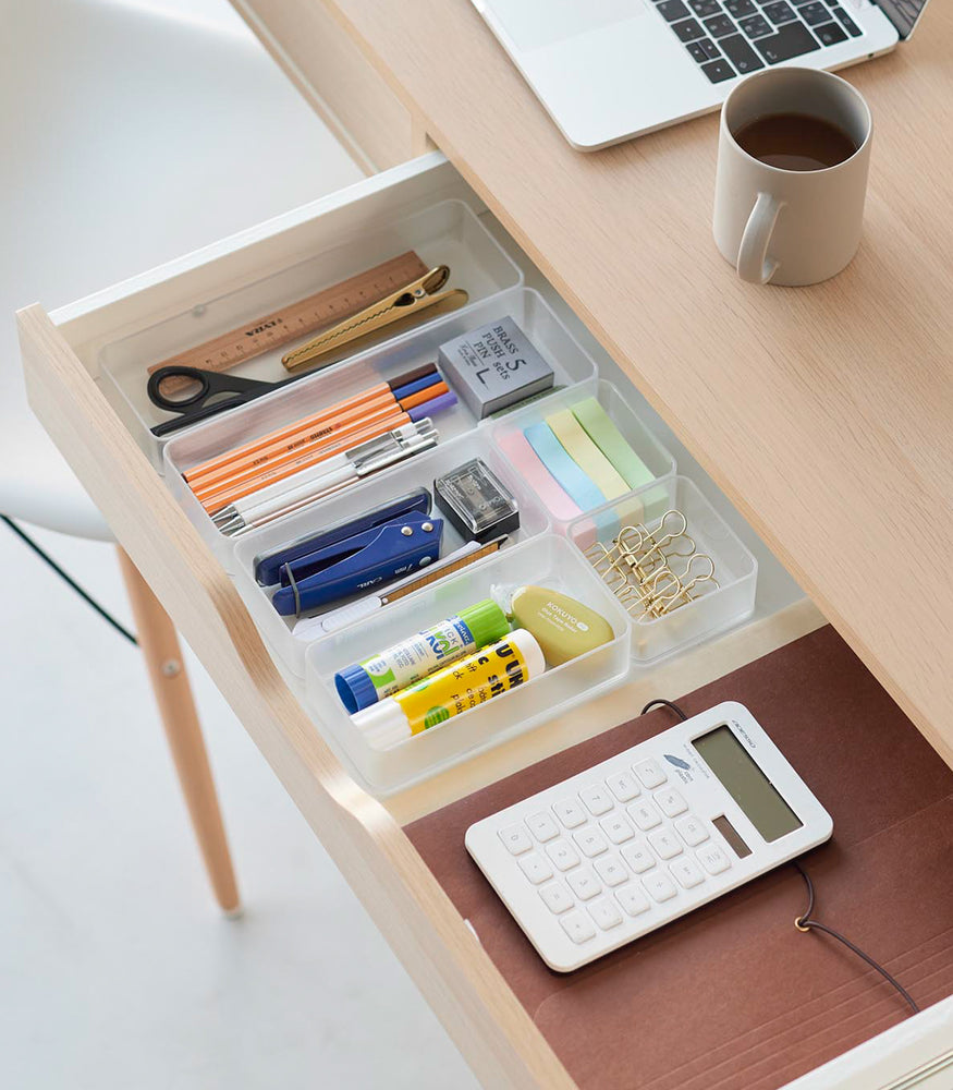 View 19 - Three different sizes of stackable clear organizers—small, medium, and large—are neatly placed in a desk drawer. Made from transparent material, they accommodate stationery items like pens, paper clips, and sticky notes, showcasing their clarity and stackability.