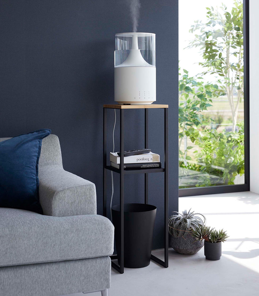 View 10 - Yamazaki black Pedestal Stand in a living room with an air purifier on top and books on the lower shelf