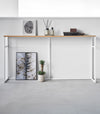 Straight view of the Long Console Table by Yamazaki Home in white placed along a wall with decorative items.
