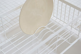 Close up view of white Over-the-Sink Expandable Dish Drying Rack holding plate in kitchen by Yamazaki Home. view 6