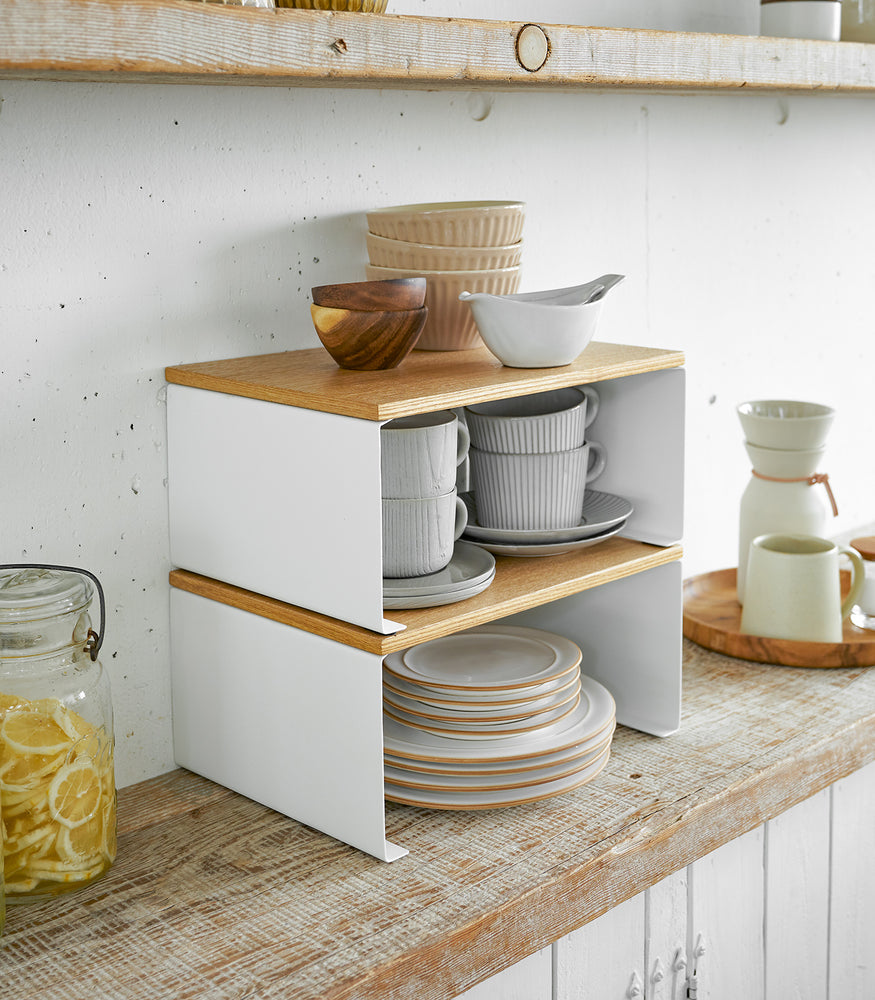 View 14 - Side view of white Stackable Countertop Shelves stacked together holding dinnerware by Yamazaki Home.