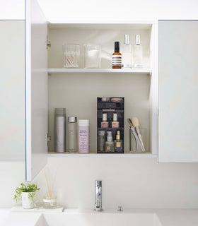 A white medicine cabinet is open to display the inside contents. Sunlight is focused on the right upper corner. Below is a bathroom sink. On the sinks ledge is a plant and oil diffuser. view 32