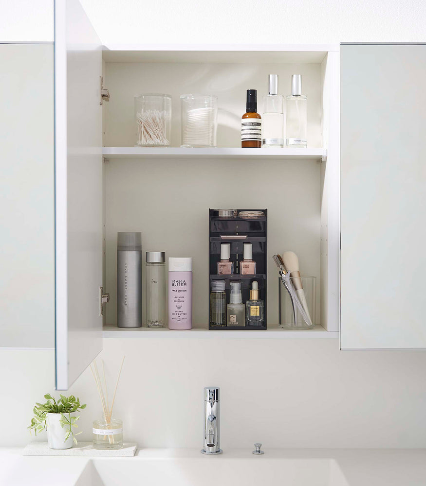 View 32 - A white medicine cabinet is open to display the inside contents. Sunlight is focused on the right upper corner. Below is a bathroom sink. On the sinks ledge is a plant and oil diffuser.