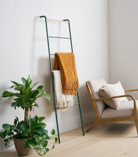 Side view of Forest Green Yamazaki Home Leaning Storage Ladder with two blankets stored view 3