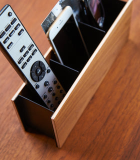 Close up view of walnut Organizer Caddy holding remote and phone by Yamazaki Home. view 8