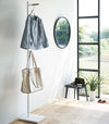 Side view of white Yamazaki Coat Rack with a purse and jacket hanging on it in an entryway
