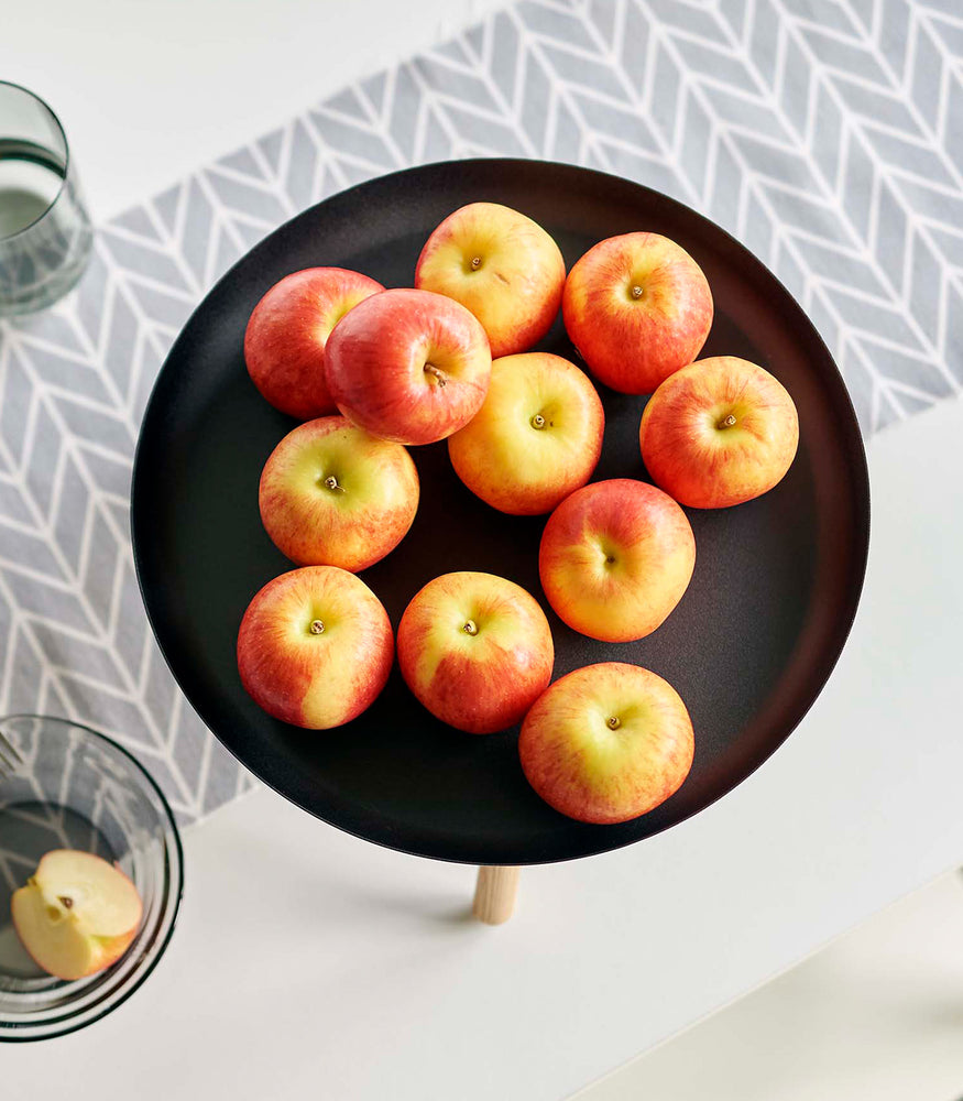View 13 - Top-down view of black Yamazaki Countertop Pedestal Tray with apples on top on a dining table