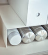 Close up of white Yamazaki Home Shelf Risers in a cabinet with water bottles