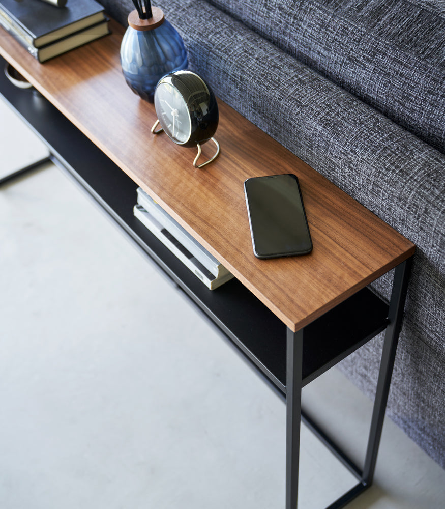 View 30 - Close up of black Yamazaki Home Long Console Table - Shelf  with a phone and clock on it