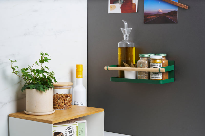 Wide shot of Forest Green Yamazaki Home Magnetic Storage Caddy with oil, herbs and spices stored attached to a refridgerator