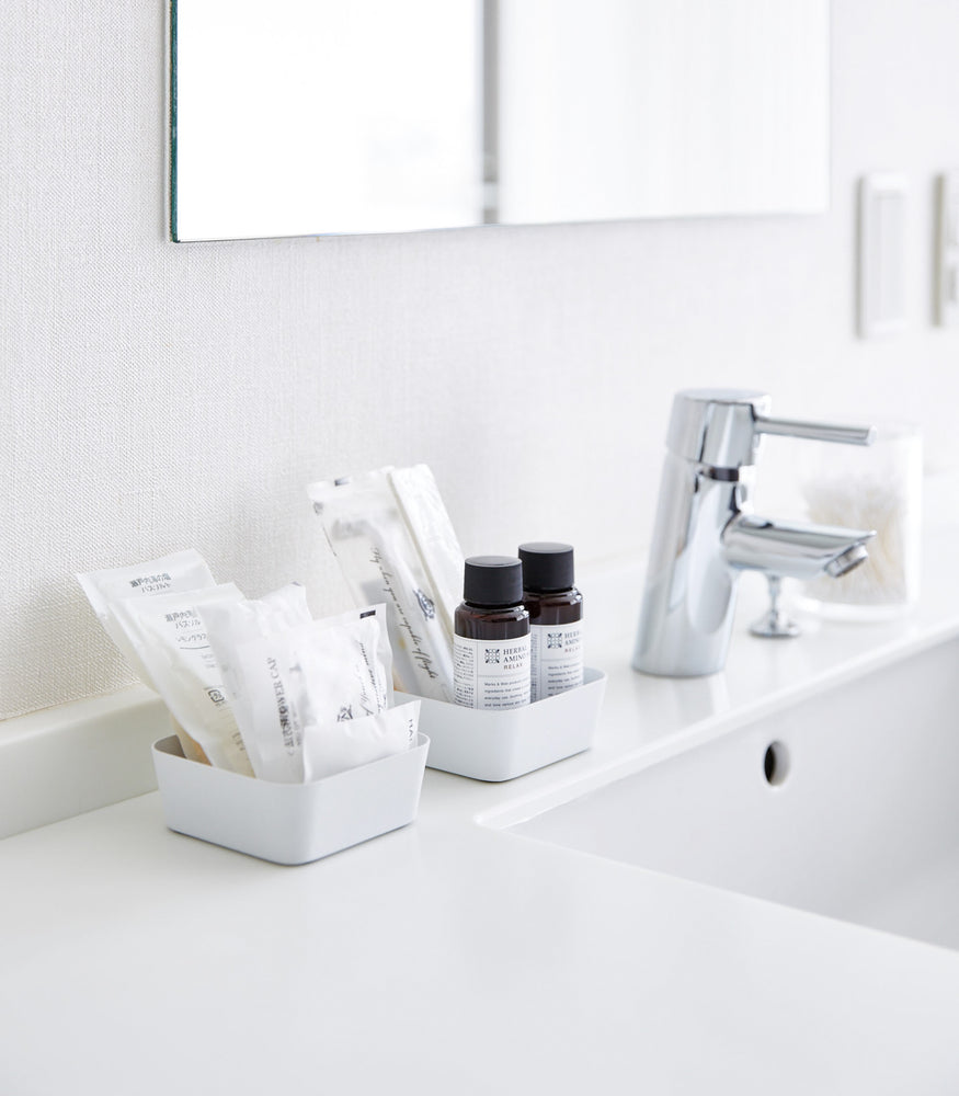 View 2 - Small white Accessory Trays holding beauty products on bathroom sink counter by Yamazaki Home.