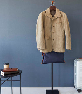 Front view of black Yamazaki Coat Rack with a jacket and messenger bag hanging on it in an entryway view 16