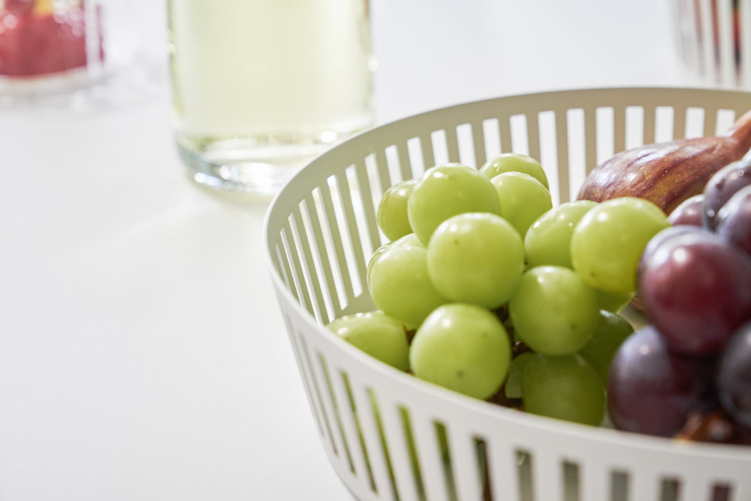 View 5 - Close up view of white Fruit Basket holding grapes by Yamazaki Home.