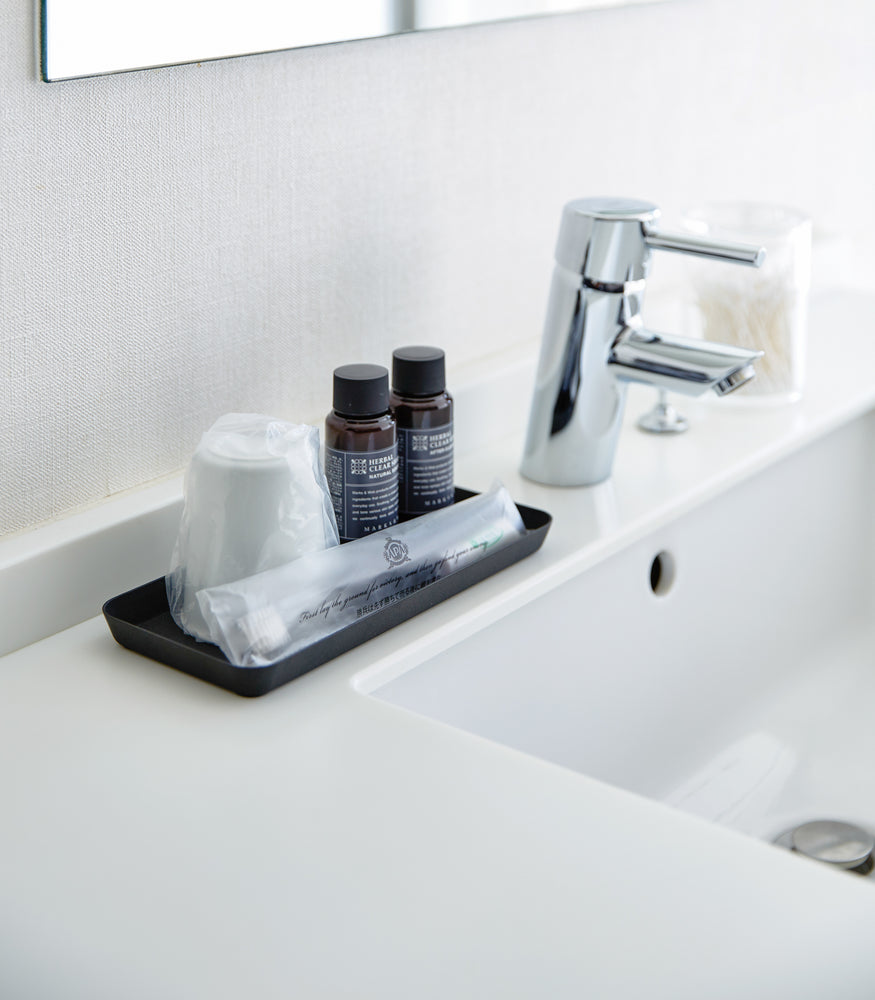 View 19 - Flat black Accessory Tray holding toothbrush, cup, and soap on bathroom sink counter.