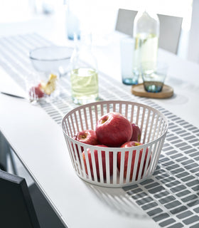 White Fruit Basket holding apples on dining room table by Yamazaki Home. view 2