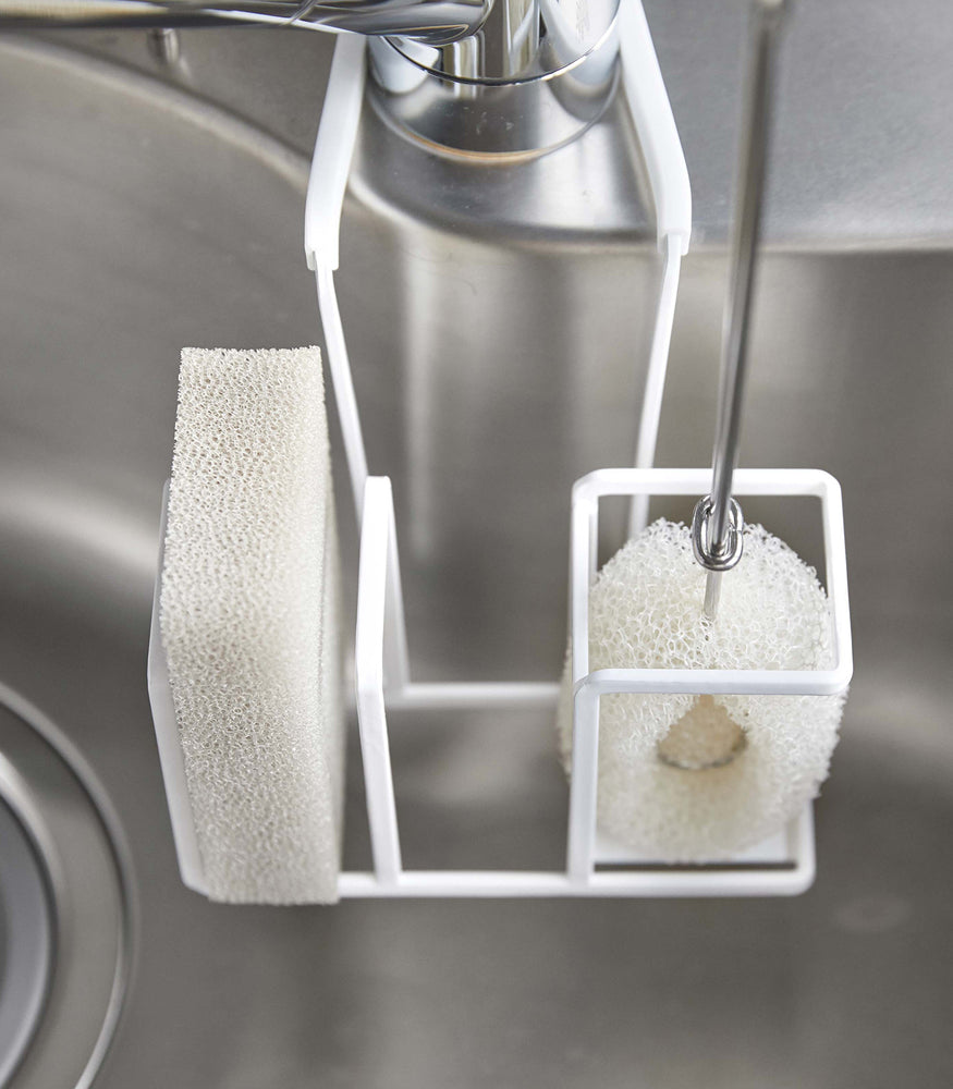 View 4 - Close up of white Steel Yamazaki Home Faucet-Hanging Sponge & Brush Holder storing a brush and a sponge