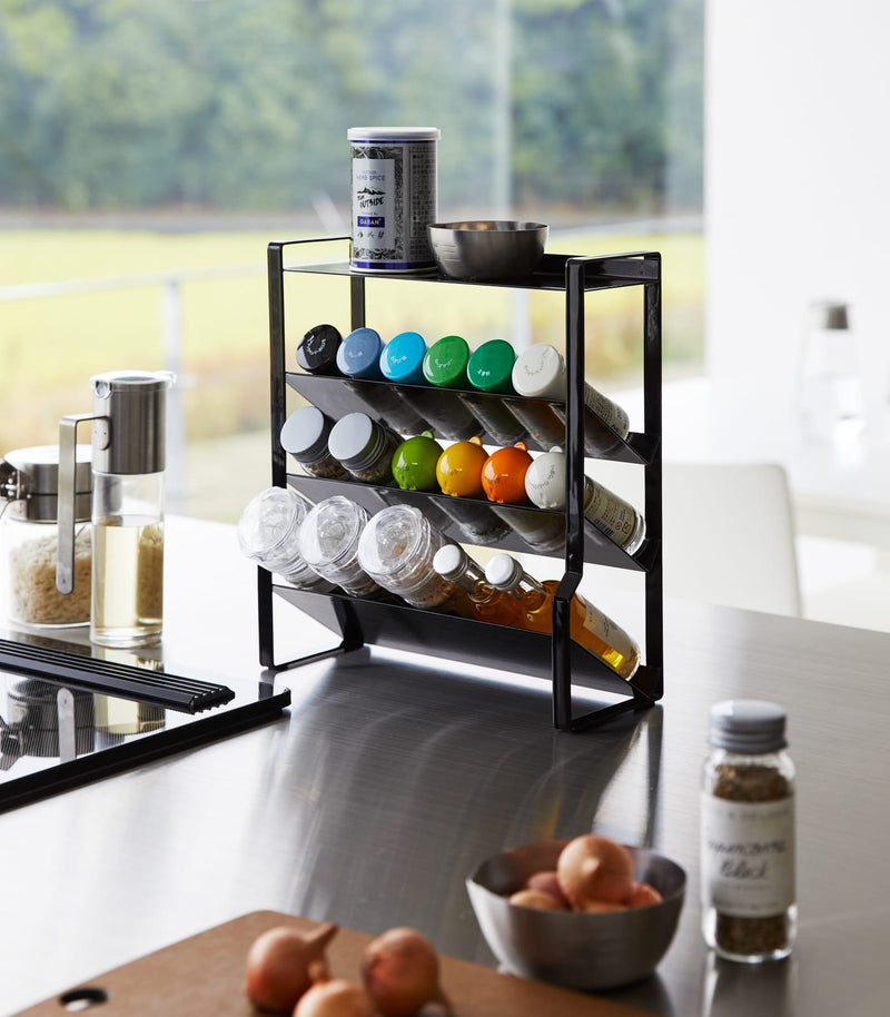 Black Four-Tier Slim Spice Rack by Yamazaki Home on a sleek kitchen counter, filled with colorful spices and kitchen essentials.