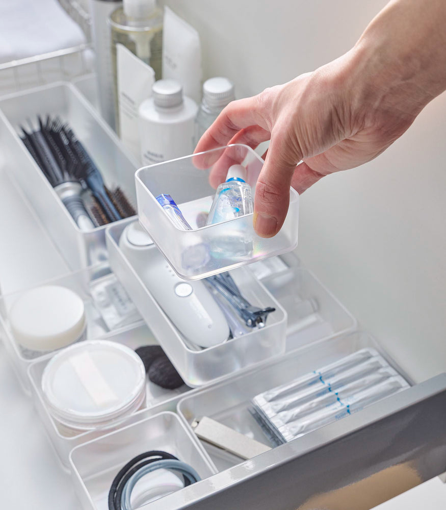 View 4 - Four different sizes of stackable clear organizers—small, medium, large, and deep—are neatly placed in a bathroom drawer. Made from transparent material, they accommodate items like brushes and sanitary products, showcasing their clarity and stackability.