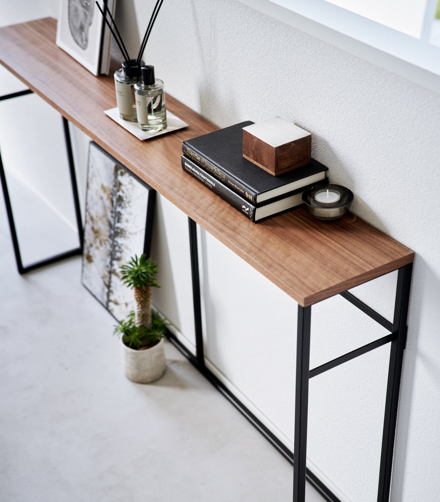 View 16 - Image showing the Long Console Table by Yamazaki Home in black from above with various decorative items on top.