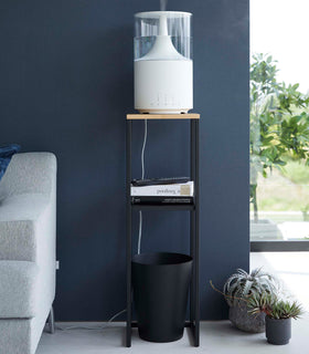Pedestal Stand in black by Yamazaki Home in a living room holding a humidifier, some books, and a waste bin on the bottom. view 14