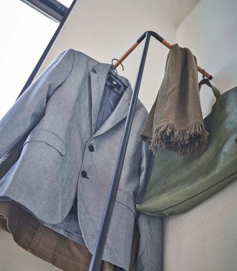 Upward view of Yamazaki black Corner Leaning Coat Hanger with clothes and other items