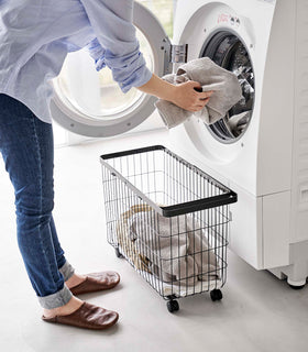A person unloading laundry from a dryier into the Rolling Wire Basket by Yamazaki Home in black. view 15