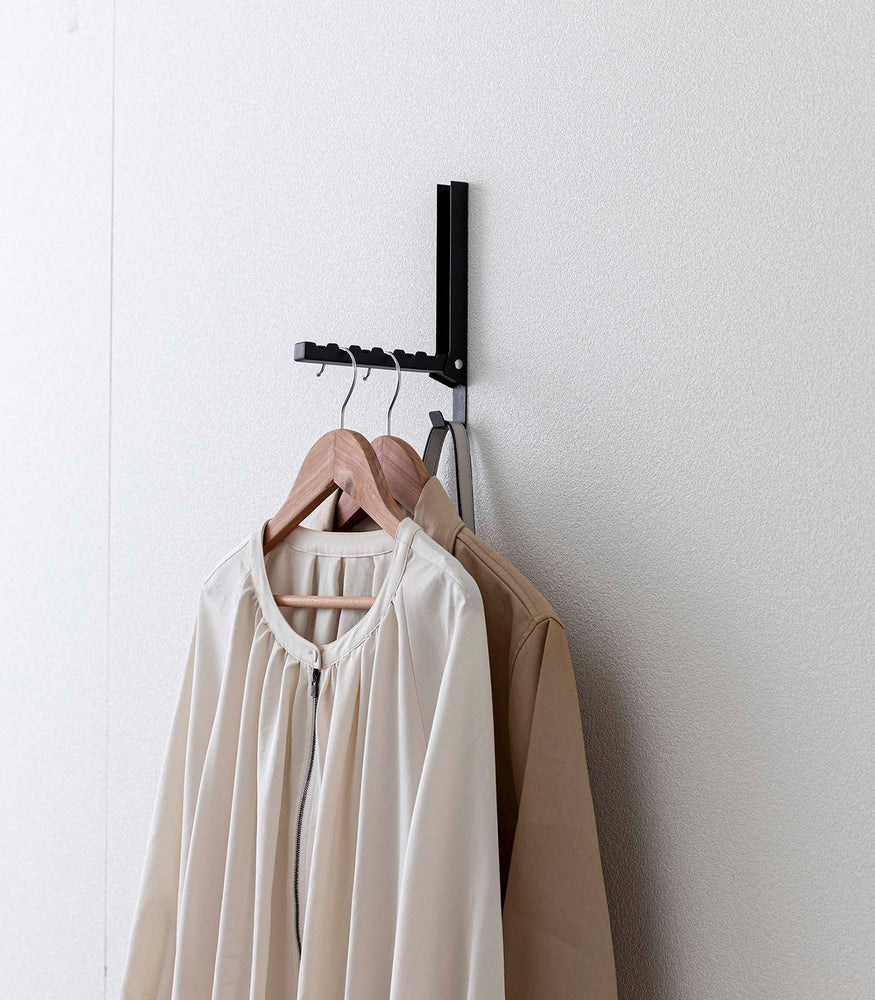 View 25 - Black Yamazaki Home Folding Over-The-Door Hanger mounted with multiple jackets hung