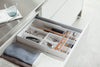 White Expandable Drawer Organizer holding kitchen utensils and silverware by Yamazaki Home.