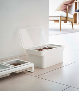 White Airtight Food Storage Container open and holding pet food next to white Pet Food Bowl by Yamazaki Home. view 4