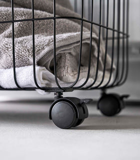Image showing bottom corner of Rolling Wire Basket by Yamazaki Home in black with two casters. view 16