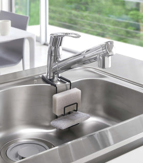 Black Faucet-Hanging Sponge Holder holding sponges in kitchen sink by Yamazaki Home. view 15