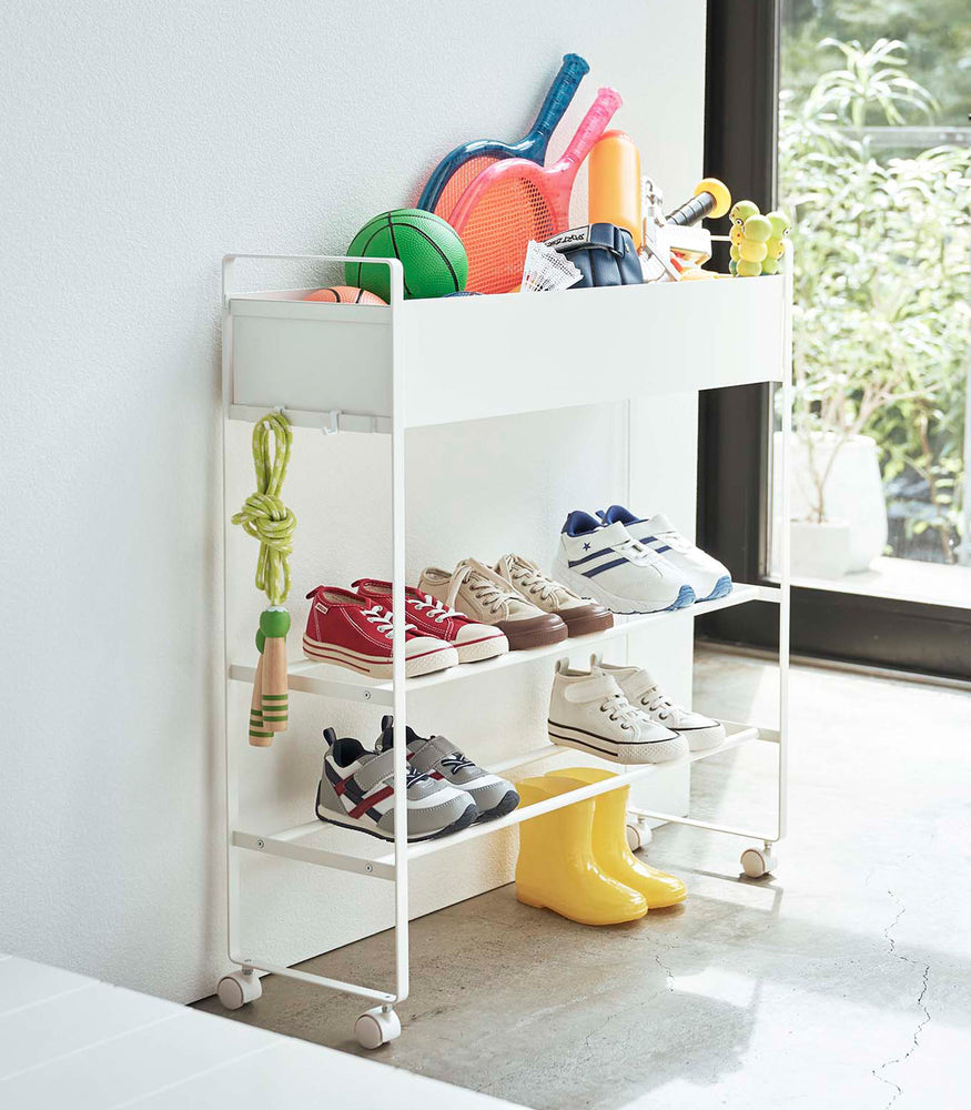 View 3 - White Yamazaki Entryway Organizer with shoes and toys on it
