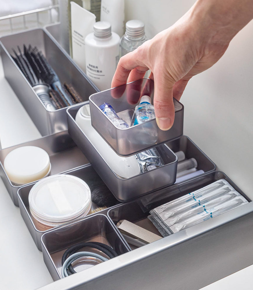 View 13 - Four different sizes of stackable clear organizers in black —small, medium, large, and deep—are neatly placed in a bathroom drawer. Made from transparent material, they accommodate items like brushes and sanitary products, showcasing their clarity and stackability.