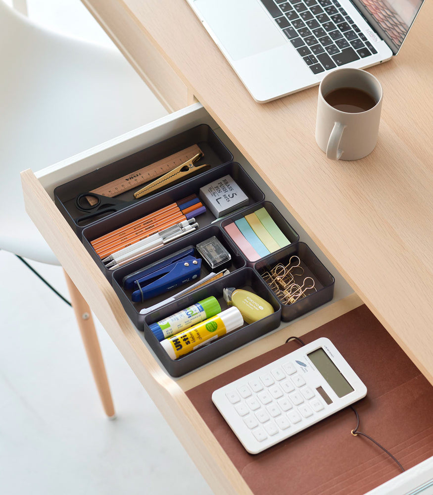 View 43 - Three different sizes of stackable clear organizers in black—small, medium, and large—are neatly placed in a desk drawer. Made from transparent material, they accommodate stationery items like pens, paper clips, and sticky notes, showcasing their clarity and stackability.