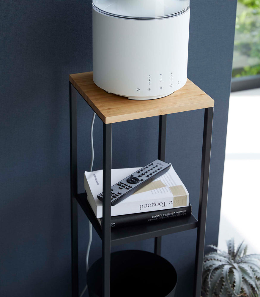 View 15 - Closeup of Yamazaki black Pedestal Stand with an air purifier, tv remote and books