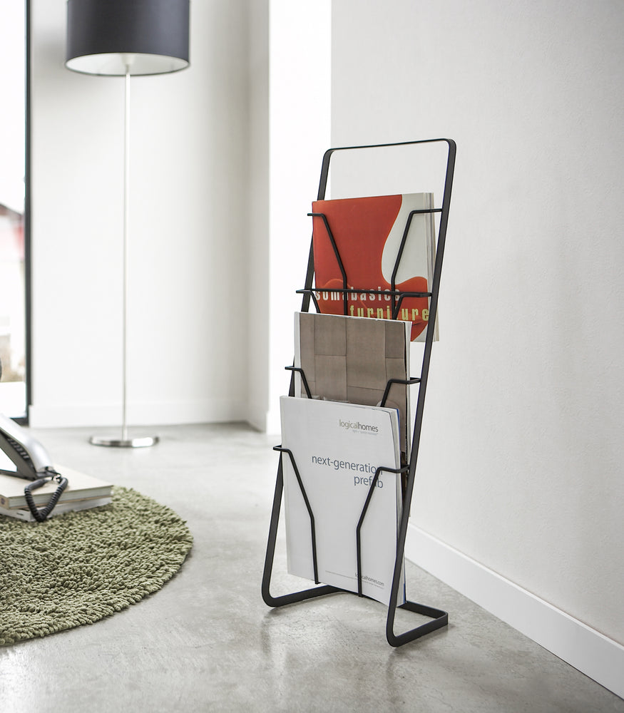 View 4 - Black Magazine Rack displaying catalogues in living room by Yamazaki Home.