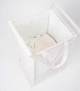 Small Laundry Hamper with Cotton Liner by Yamazaki Home in white on a white background with white towels inside. view 3