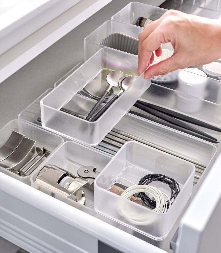 View 18 - Four different sizes of stackable clear organizers—small, medium, large, and deep—are neatly placed in a kitchen drawer. They effectively organize various items such as cutlery, bottle openers, and small trays, showcasing their versatility and stackability