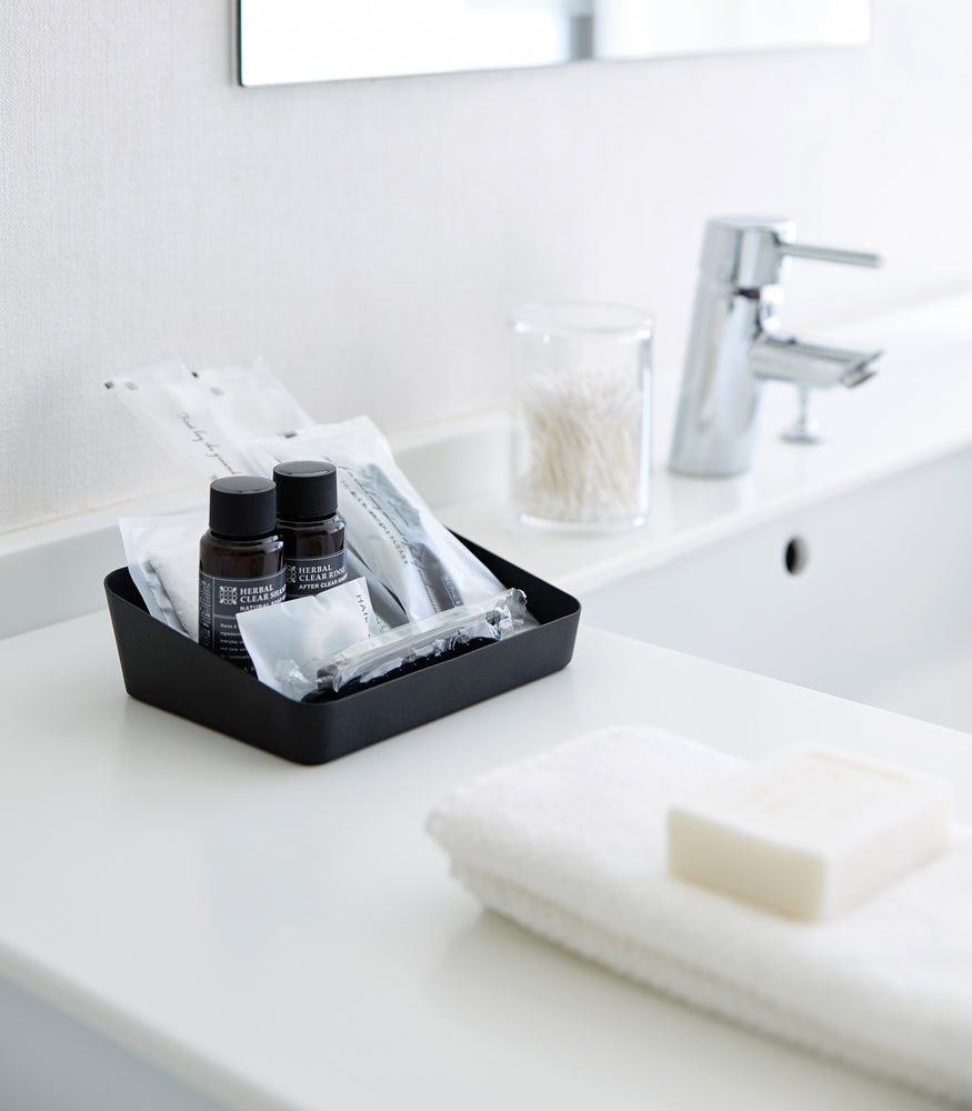 View 7 - Medium black Accessory Tray holding beauty items on bathroom sink counter by Yamazaki Home.
