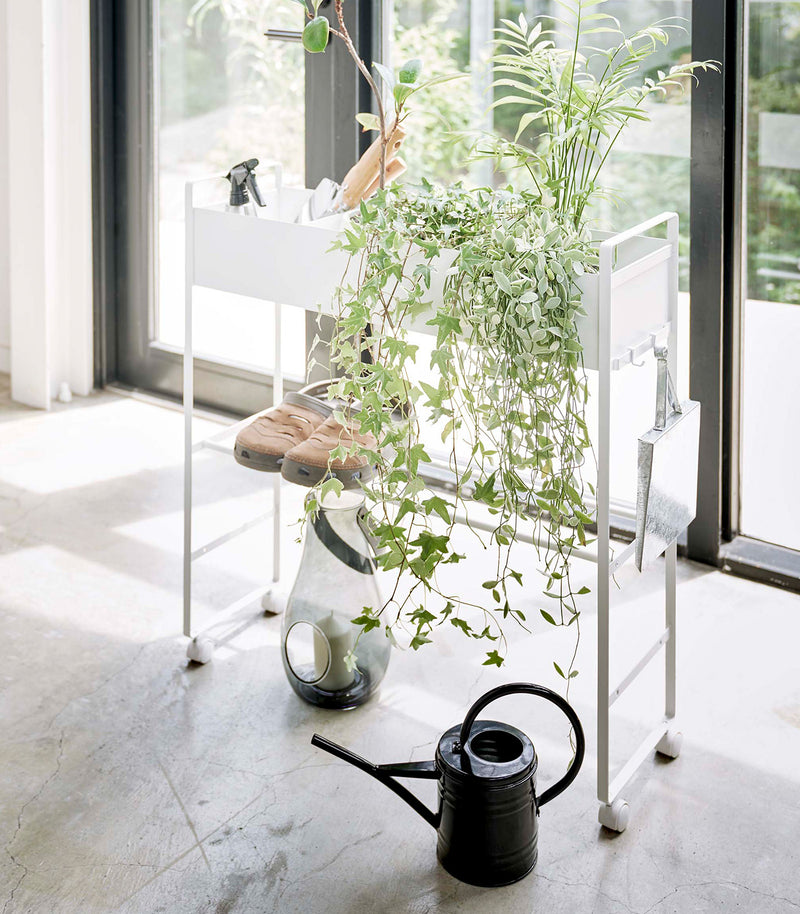 White Yamazaki Entryway Organizer with shoes, plants and gardening tools on it