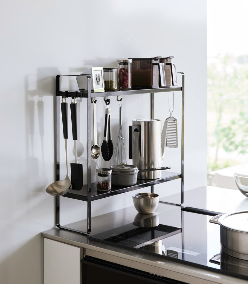 Yamazaki Home Two-Tier Countertop Rack holding spices and kitchen utensils.