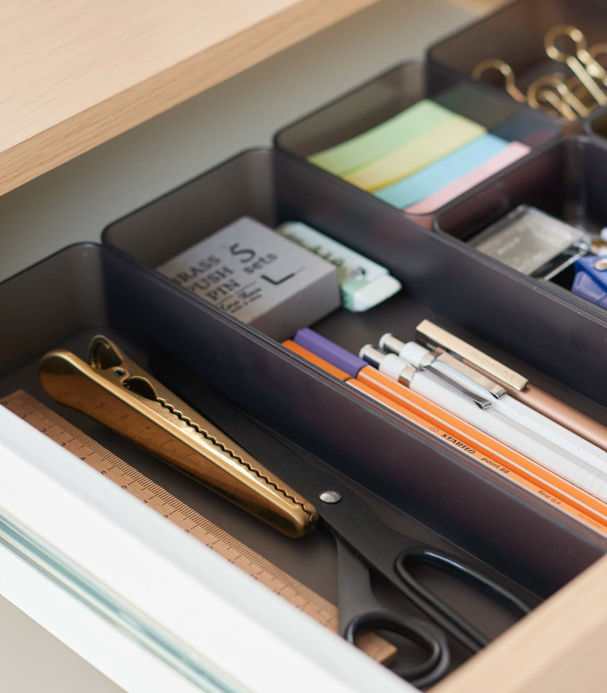 View 46 - Close-up image of three different sizes of stackable clear organizers in black—small, medium, and large—neatly placed in a desk drawer. Made from transparent material, they accommodate stationery items like pens, paper clips, and sticky notes, showcasing their clarity and stackability