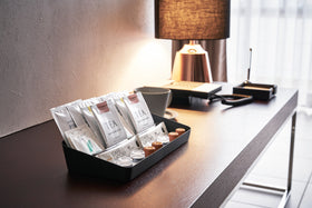 Side view of black Accessory Tray holding tea bags and coffee pods on desk by Yamazaki Home. view 16