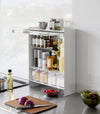 Diagonal view of the Concealable Spice Rack in white by Yamazaki Home with the front panel open, showing various spices and condiments inside.