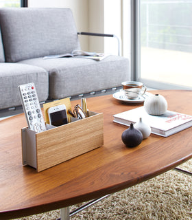 Ash Organizer Caddy holding remote, phone, and glasses on coffee table by Yamazaki Home. view 3