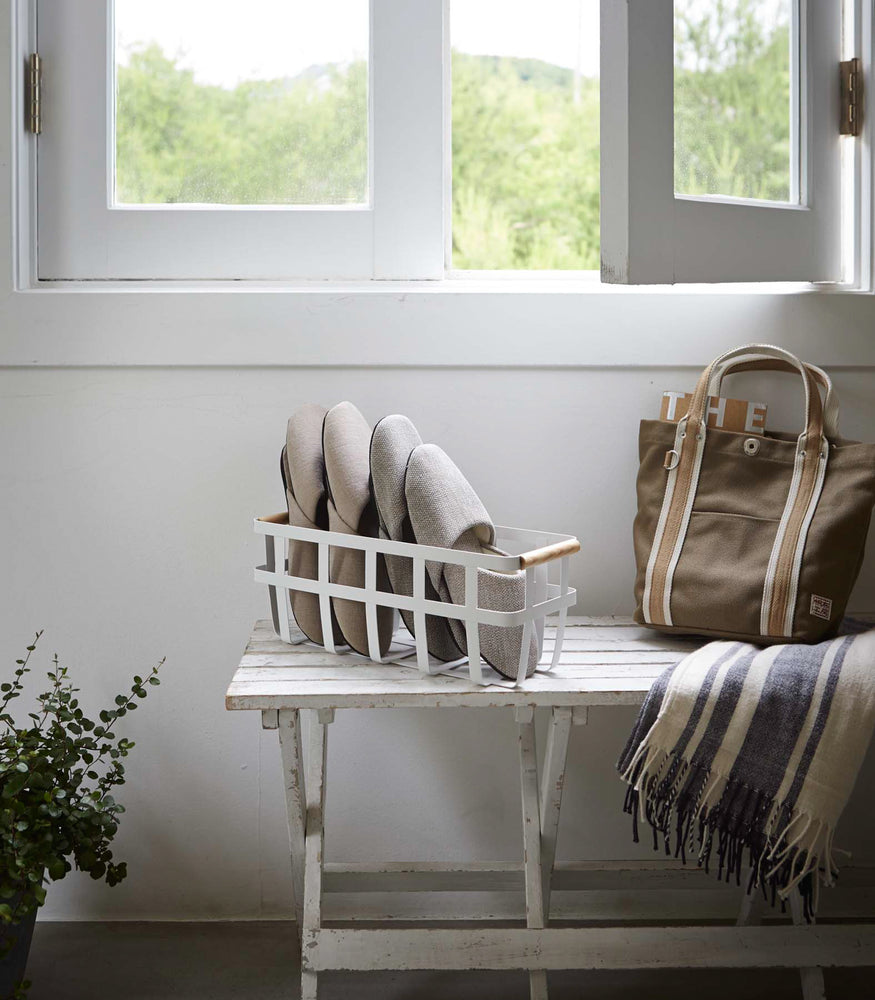 View 3 - White Storage Basket containing slippers on bench by Yamazaki Home.