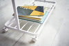 Close up bottom of white Rolling Coat Rack holding books by Yamazaki Home.