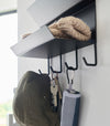 Close-up of the hooks on the Magnetic Entryway Rack by Yamazaki Home in black. Various entryway items are stored on the rack including keys and an umbrella.