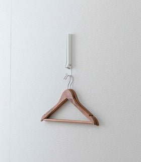 White Yamazaki Home Folding Over-The-Door Hanger mounted closed with hangers hung view 18